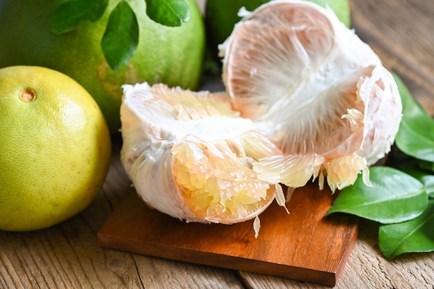 Fresh green pomelo peeled and leaf frome pomelo tree pomelo fruit on wooden plate background pummelo grapefruit in summer tropical fruit in thailand