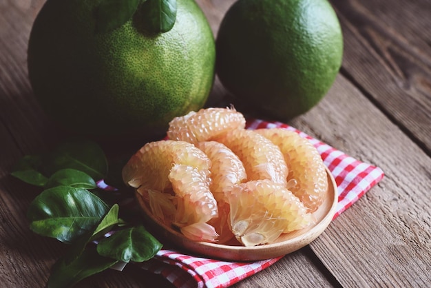 Fresh green pomelo peeled and leaf frome pomelo tree pummelo grapefruit in summer tropical fruit in thailand pomelo fruit on wooden plate background