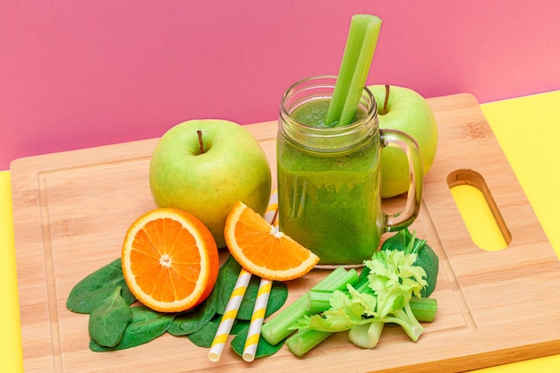 Fresh green smoothie of apple celery spinach and orange in glass smoothie jar