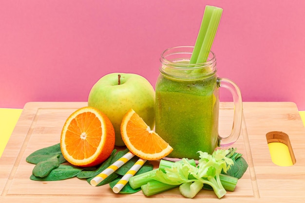 Fresh green smoothie of apple celery spinach and orange in glass smoothie jar