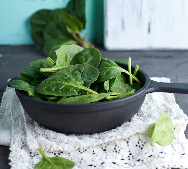 Fresh green spinach in a round cast-iron frying pan