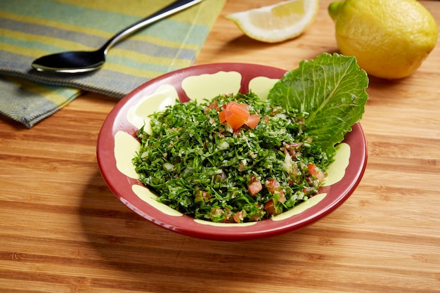 Fresh green Taboule or tabbouleh with tomato green leaf and lime slice served in dish isolated on table side view of middle east food