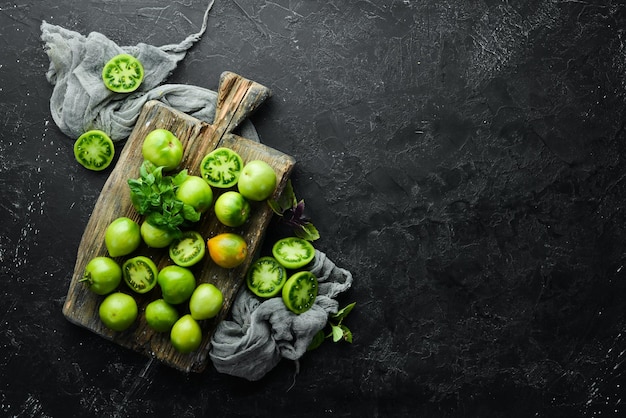 Fresh green tomatoes on black stone background Green vegetables Top view Free space for your text