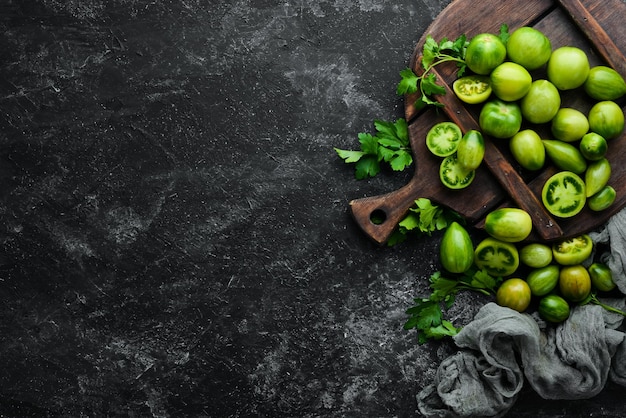 Fresh green tomatoes on black stone background Green vegetables Top view Free space for your text