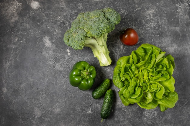 Fresh green vegetables on a dark background, top view with copy space.