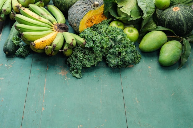 Fresh green vegetables and fruits on green wooden background