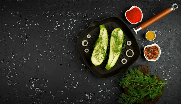 Fresh green zucchini in a pan on a dark table. The view from the top. Copy space.