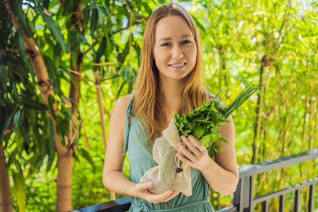 Fresh greens in a reusable bag in the hands of a young woman zero waste concept