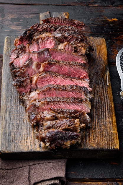 Fresh grilled meat Grilled beef steak medium rare black angus rib eye steak set on wooden serving board on old dark wooden table background