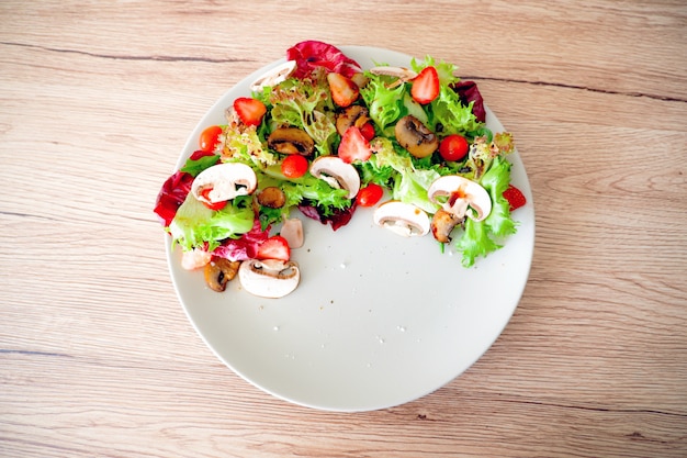 Fresh grilled mushroom salad in white plate on wood