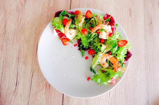 Fresh grilled shrimp salad in white plate on wood