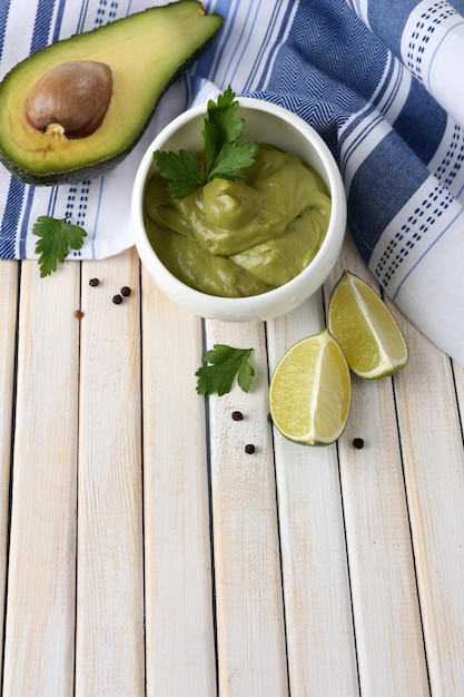 Fresh guacamole in bowl on wooden table