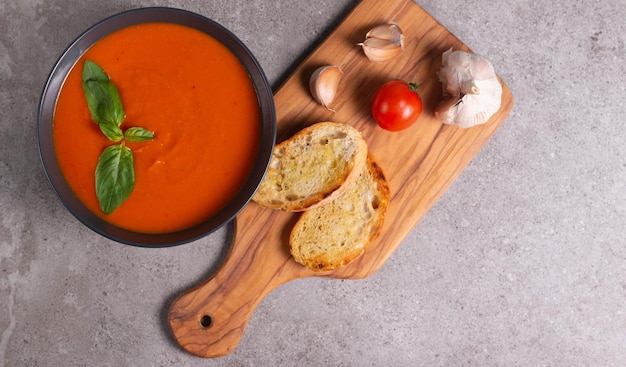 Fresh healthy tomato soup with basil pepper garlic tomatoes and bread on wooden background Spanish gazpacho soup Lentils and pumpkin soup