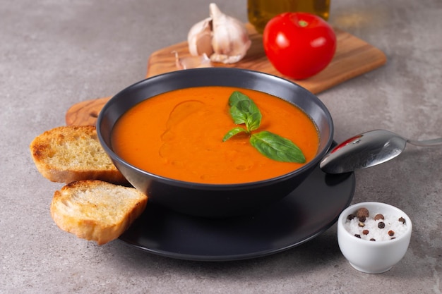 Fresh healthy tomato soup with basil pepper garlic tomatoes and bread on wooden background Spanish gazpacho soup Lentils and pumpkin soup