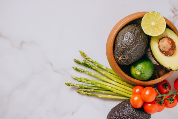 Fresh healthy vegetables in wooden plate on white marble background