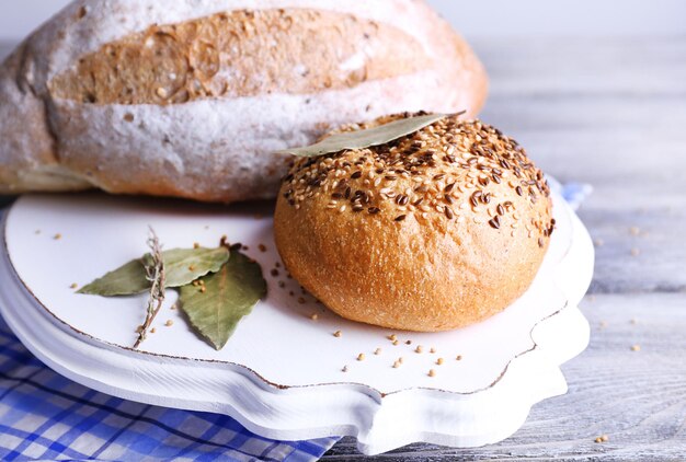 Fresh homemade bread wrapped in paper on napkin on color wooden background