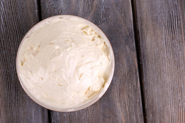 Photo fresh homemade butter in bowl on color wooden background