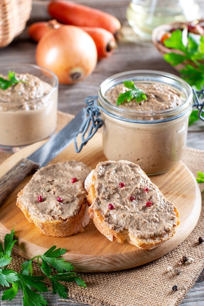 Fresh homemade chicken liver pate on bread on rustic wooden background