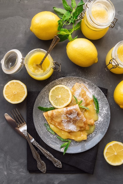 Fresh homemade crepes with lemon curd on grey concrete surface. Top view.