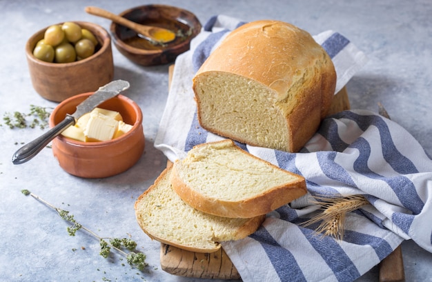 Fresh homemade crisp bread  and slices with olive oil, butter and green olives, top view.  Baking 