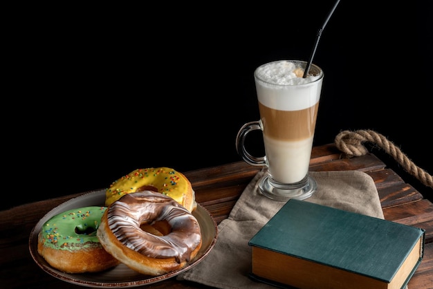 Fresh Homemade Donuts and Coffee on a wooden board In the foreground is a book 45 view