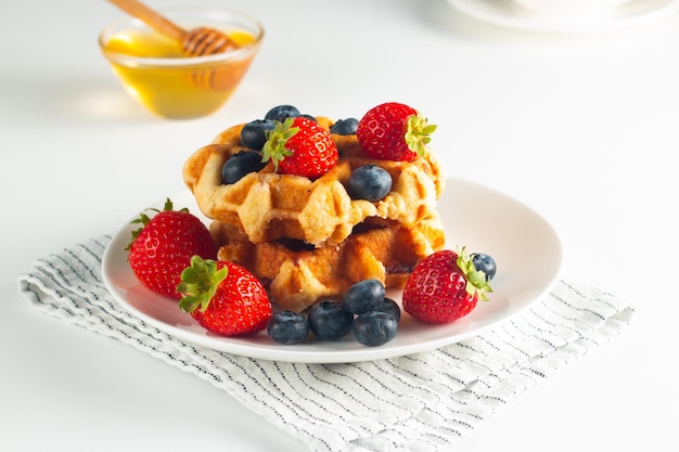 Fresh homemade food of berry Belgian waffles with honey, chocolate, strawberry, blueberry, maple syr