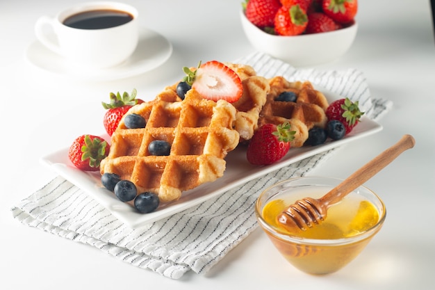 Fresh homemade food of berry Belgian waffles with honey chocolate strawberry blueberry