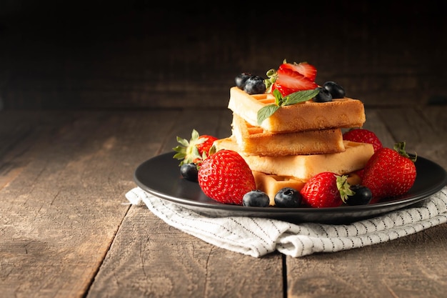 Fresh homemade food of berry Belgian waffles with honey chocolate strawberry blueberry