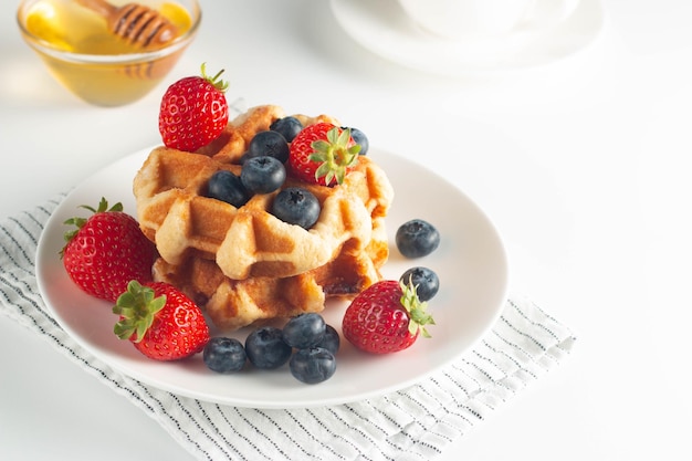 Fresh homemade food of berry Belgian waffles with honey chocolate strawberry blueberry