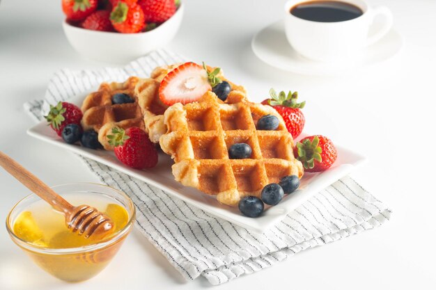 Fresh homemade food of berry Belgian waffles with honey chocolate strawberry blueberry