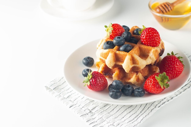 Fresh homemade food of berry Belgian waffles with honey strawberry blueberry and syrup