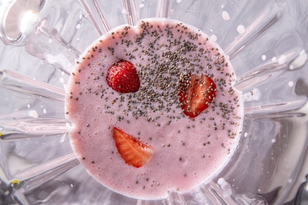 Fresh homemade milkshake from strawberries, milk and chia seeds in a glass bowl of a blender cooked. Superfoods and healthy lifestyle or detox diet food concept. Top view