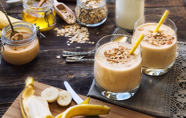 Fresh homemade nutritional smoothie with banana oat flakes and peanut butter on wooden background