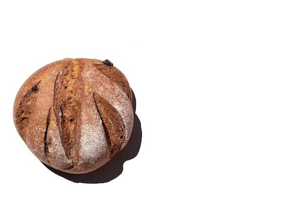 Fresh homemade rustic rye round with raisins bread isolated on white surface, top view, copy space.