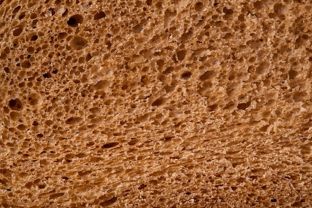 Fresh homemade rye bread. Bread texture. Traditional spelled sourdough bread cut into slices on a rustic wooden background. Concept of traditional leavened bread baking methods. Selective focus.