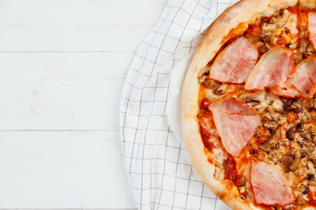 Fresh homemade sliced pizza on white wooden table top view