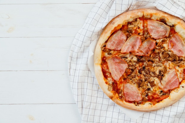 Fresh homemade sliced pizza on white wooden table top view