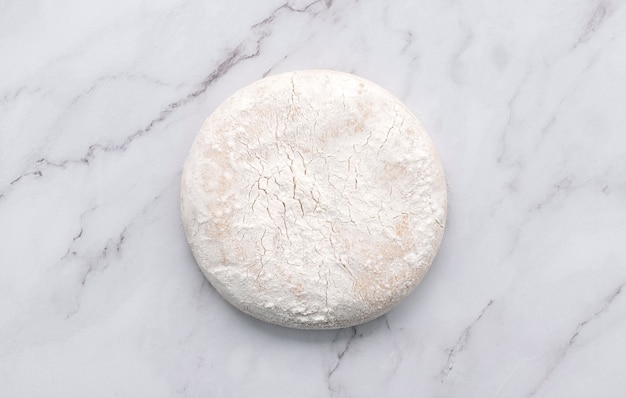 Fresh homemade yeast dough resting on marble table flat lay.