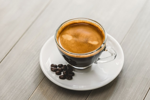 Fresh hot cup of brewed espresso coffee served on a saucer in vintage wooden table