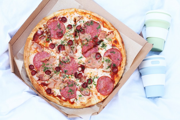 Fresh hot pizza with tomato sauce and bacon at a picnic