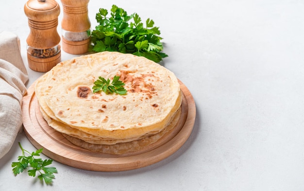 Fresh Indian chapati tortillas with fresh parsley on a gray background