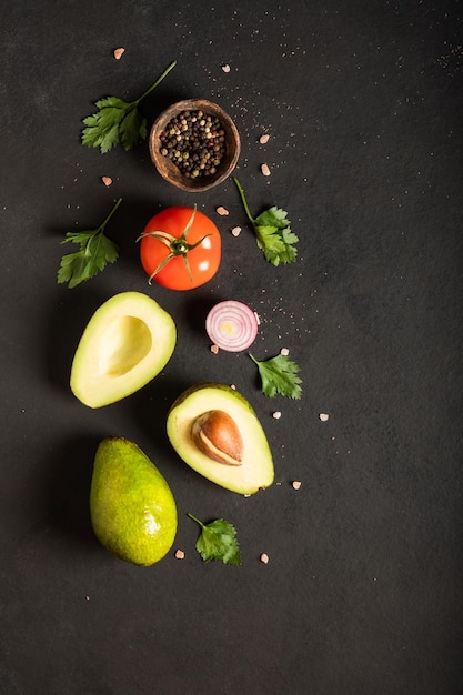 Fresh  ingredients for guacamole avocado tomatored onion cilantro on a black background