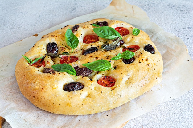 Fresh Italian flat bread Focaccia with tomatoes, olives, garlic and herbs.