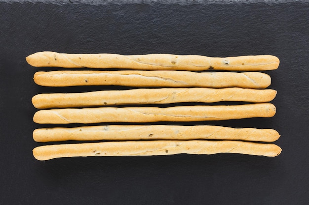 Fresh Italian Grissini Breadsticks served on black background Dry baked bread with olive pieces