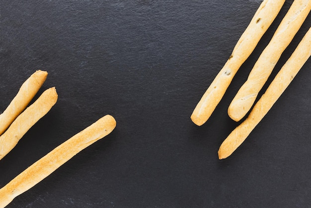 Fresh Italian Grissini Breadsticks served on black background Dry baked bread with olive pieces