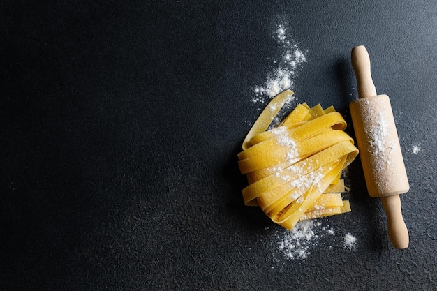 Photo fresh italian pasta papardelle with flour on dark background top view