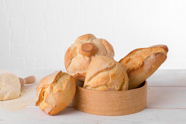 Fresh italian wheat breads in the sieve on the table with flour and dough on white background