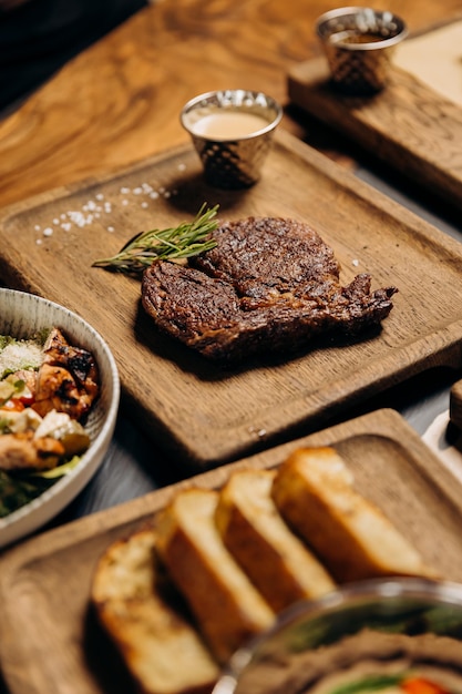 Fresh juicy delicious beef steak on wooden background in restaurant Meat dish with spices and herbs