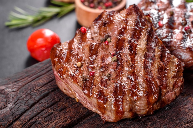 Fresh juicy delicious beef steak on wooden table. Meat dish with spices and herbs