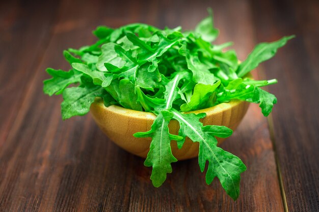 Fresh juicy leaves of arugula on a brown wooden table.